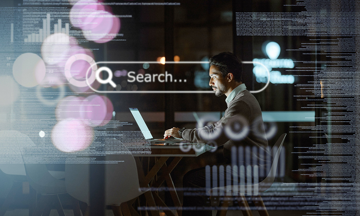 A man sitting at a desk with a laptop with text surrounding him and a search box.